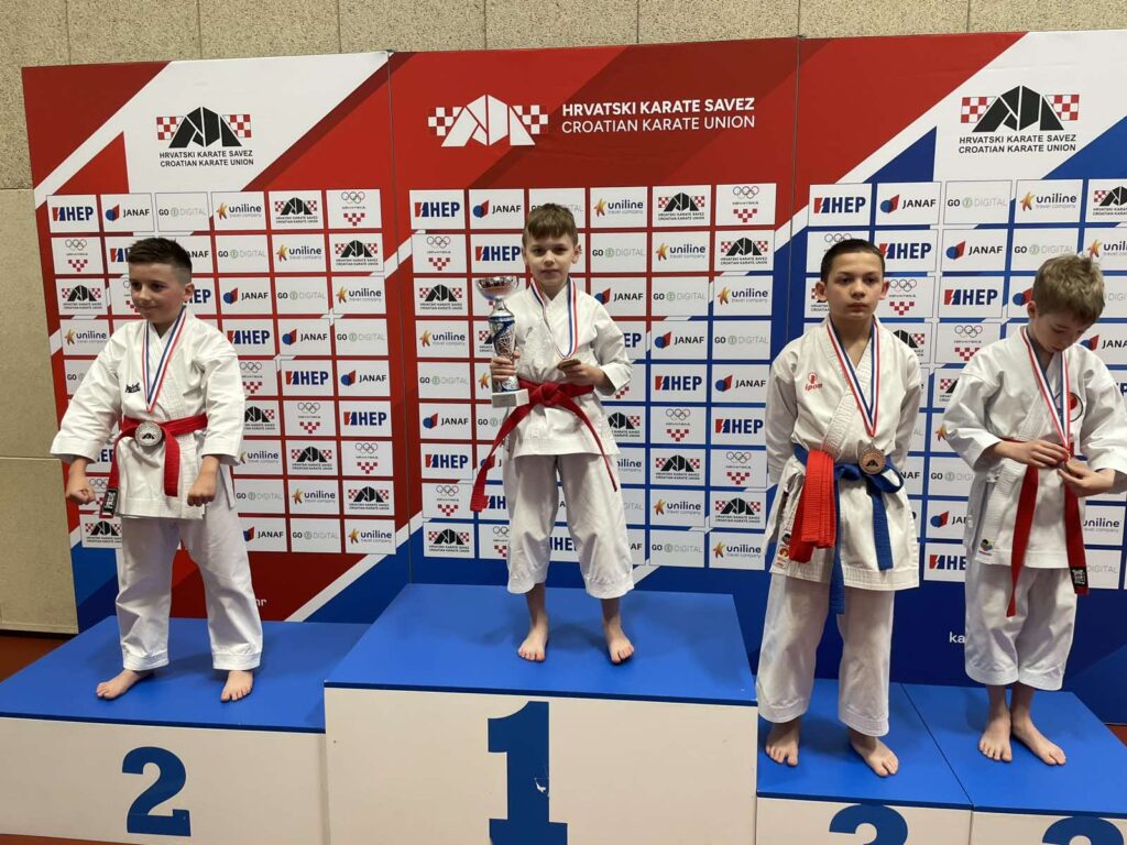 Teo Biškup sa zlatom oko vrata i s peharom u društvu drugo i trećeplasiranog